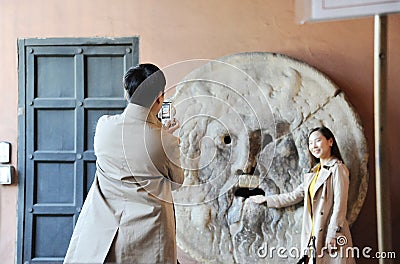 Asian man and woman photograph each other in front of the mouth of truth Bocca della VeritÃ . Editorial Stock Photo